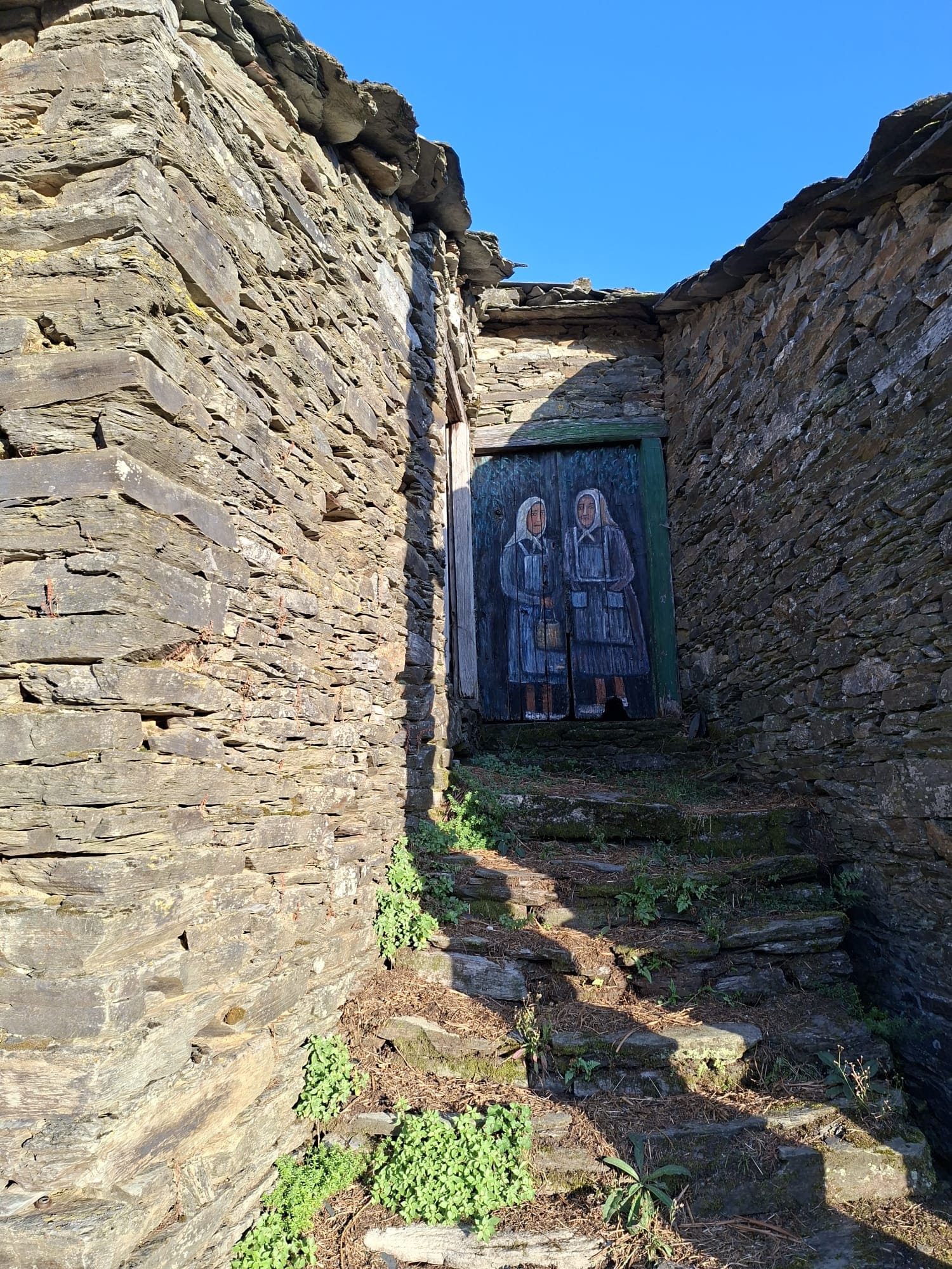 Puerta pintada con motivos de colores en una vivienda tradicional de la aldea de Parada