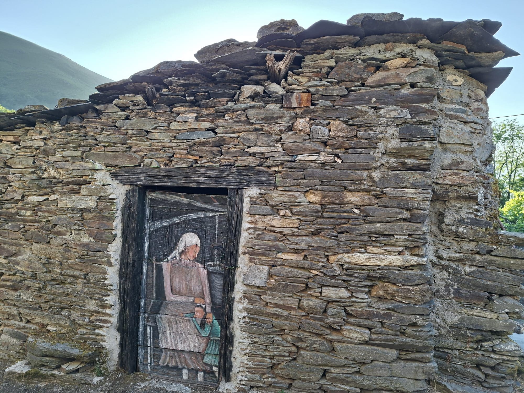 Fachada de pedra com porta pintada no centro da aldeia de Parada, O Courel